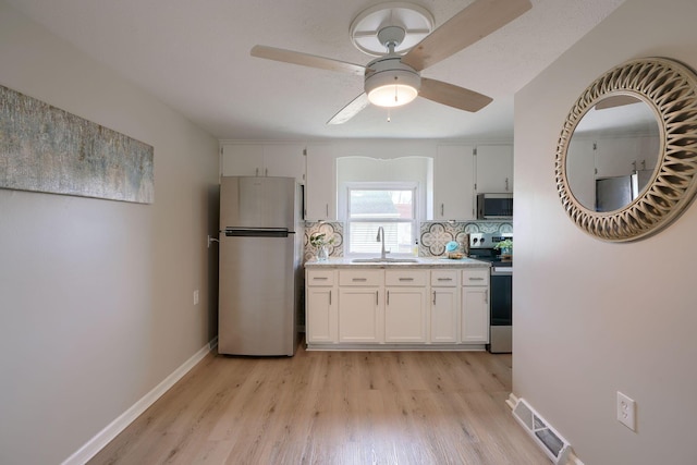 kitchen with baseboards, visible vents, light wood-style flooring, stainless steel appliances, and a sink