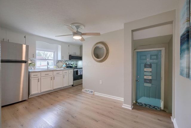 kitchen with visible vents, appliances with stainless steel finishes, white cabinetry, a sink, and light wood-type flooring