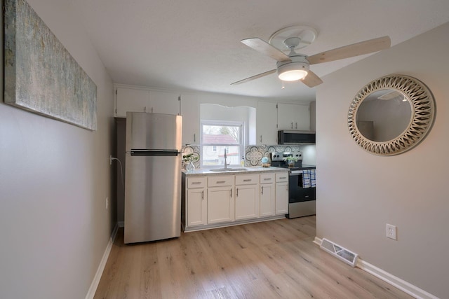 kitchen featuring visible vents, light wood-style flooring, stainless steel appliances, light countertops, and a sink