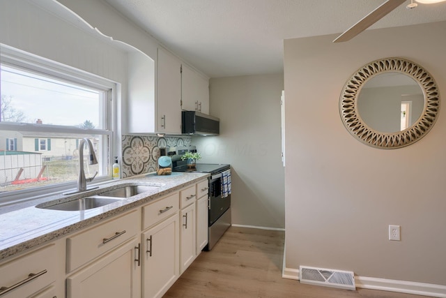 kitchen featuring light stone counters, electric range, a sink, visible vents, and light wood-style floors