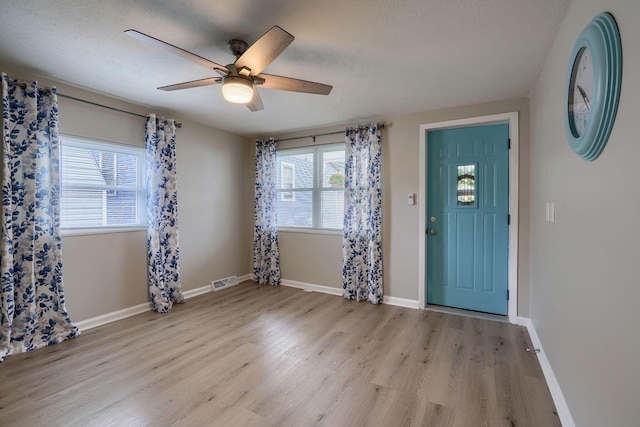 foyer featuring a textured ceiling, wood finished floors, visible vents, and baseboards