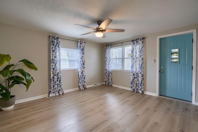 entrance foyer featuring visible vents, baseboards, a ceiling fan, wood finished floors, and a textured ceiling