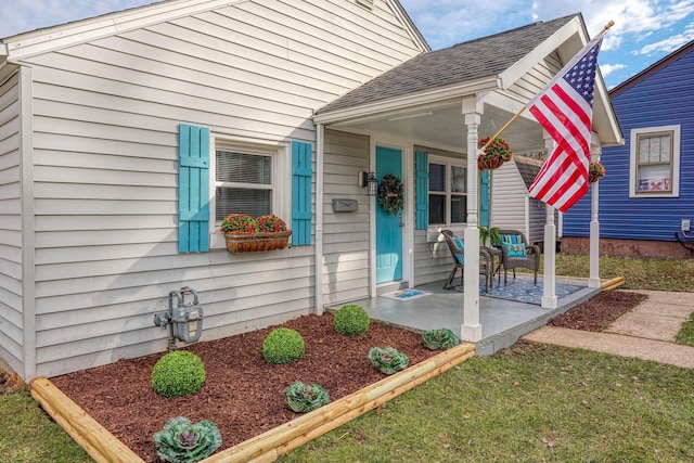 property entrance with covered porch and roof with shingles