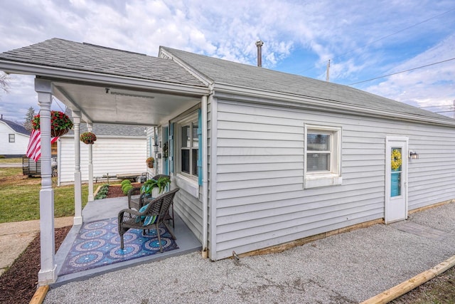 view of side of property featuring a patio and roof with shingles