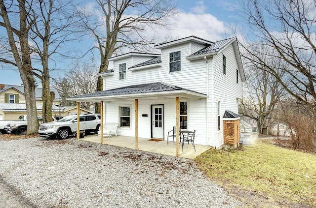 view of front of house with covered porch, a front lawn, and metal roof