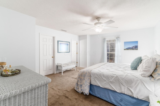 carpeted bedroom featuring a textured ceiling, ceiling fan, and visible vents