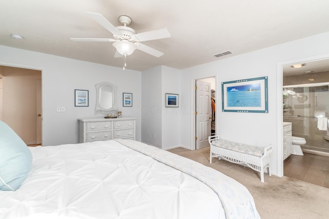 carpeted bedroom featuring visible vents, ceiling fan, a spacious closet, and ensuite bath