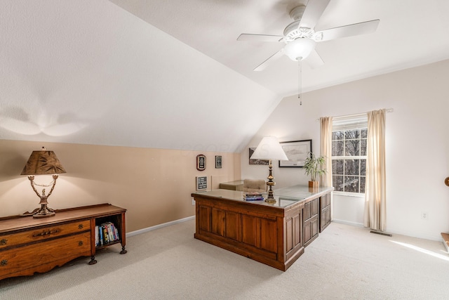 office space with vaulted ceiling, baseboards, a ceiling fan, and light colored carpet