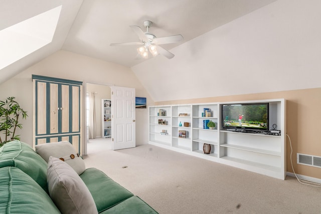 carpeted living area with ceiling fan, lofted ceiling with skylight, visible vents, and baseboards