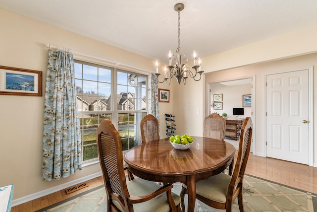 dining area with visible vents, a notable chandelier, baseboards, and wood finished floors