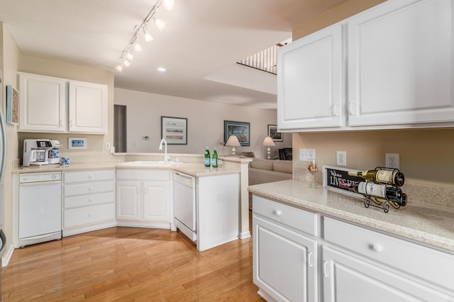 kitchen with white dishwasher, a sink, light wood-style flooring, and white cabinetry