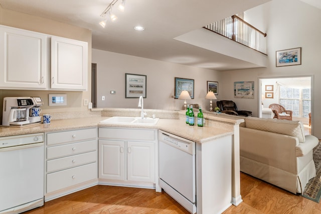 kitchen with dishwasher, a peninsula, open floor plan, and a sink