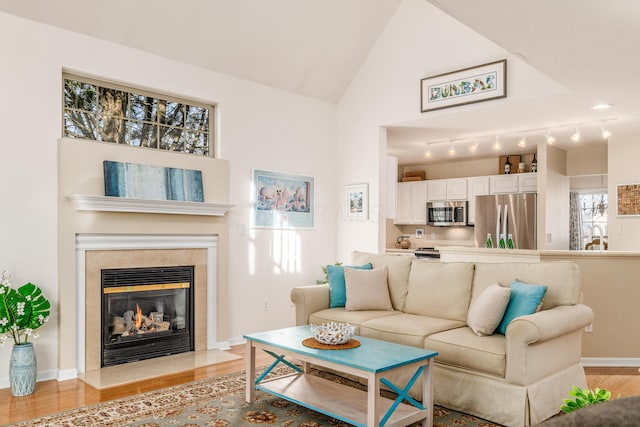 living room featuring light wood-style floors, vaulted ceiling, and a tile fireplace