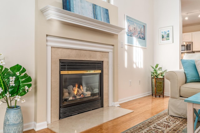 sitting room featuring a fireplace, wood finished floors, and baseboards