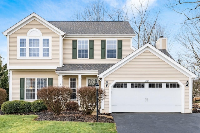 view of front of house featuring aphalt driveway, a shingled roof, a chimney, and a garage