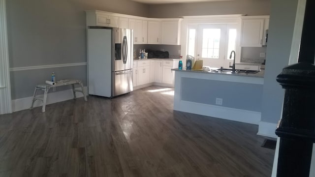 kitchen featuring stainless steel fridge, white cabinetry, light countertops, and a sink