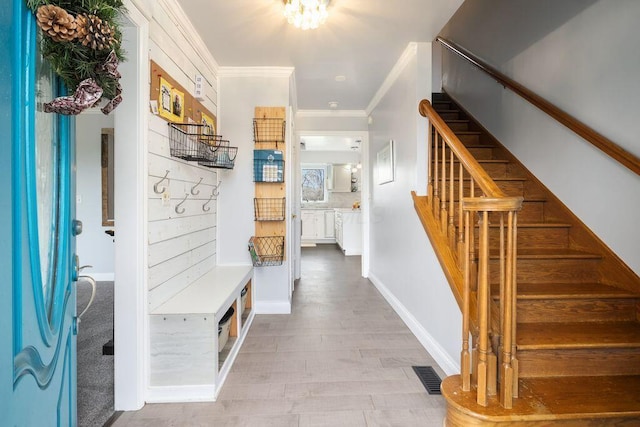 mudroom with baseboards, wood finished floors, visible vents, and crown molding