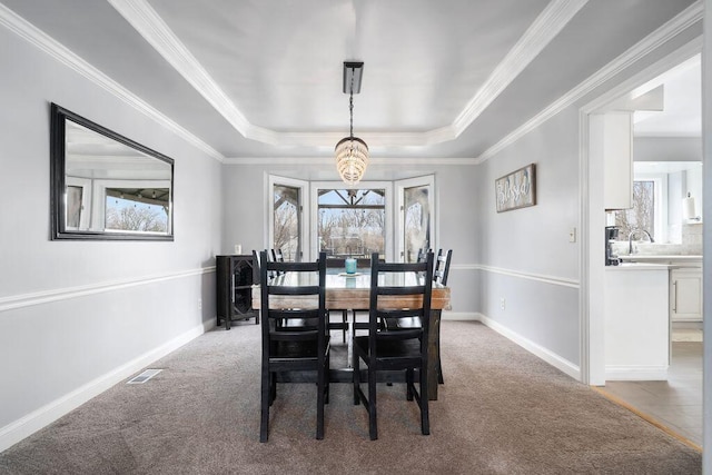 dining room with baseboards, a tray ceiling, a healthy amount of sunlight, and light colored carpet