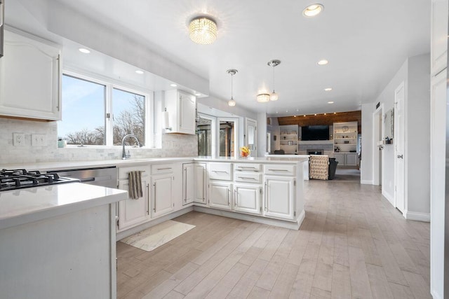 kitchen with white cabinets, open floor plan, decorative light fixtures, a peninsula, and light countertops