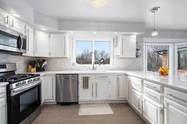 kitchen featuring appliances with stainless steel finishes, light countertops, white cabinets, and a sink