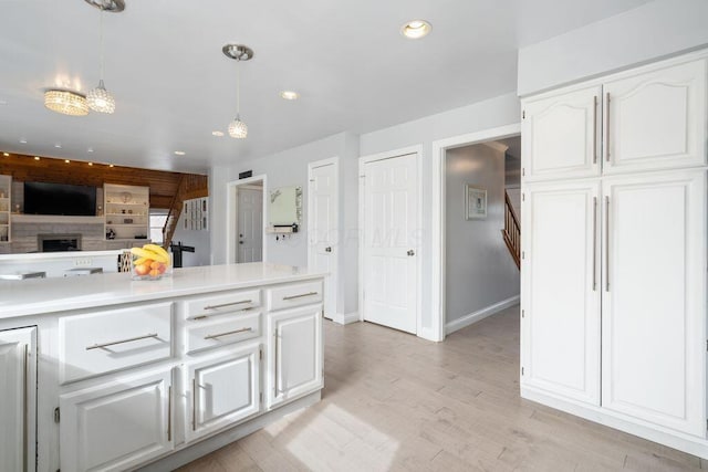 kitchen featuring light wood-style flooring, recessed lighting, white cabinets, light countertops, and hanging light fixtures