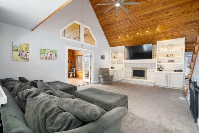 carpeted living room featuring ceiling fan, high vaulted ceiling, a stone fireplace, and built in features