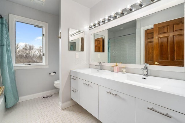 bathroom featuring toilet, double vanity, a sink, and visible vents