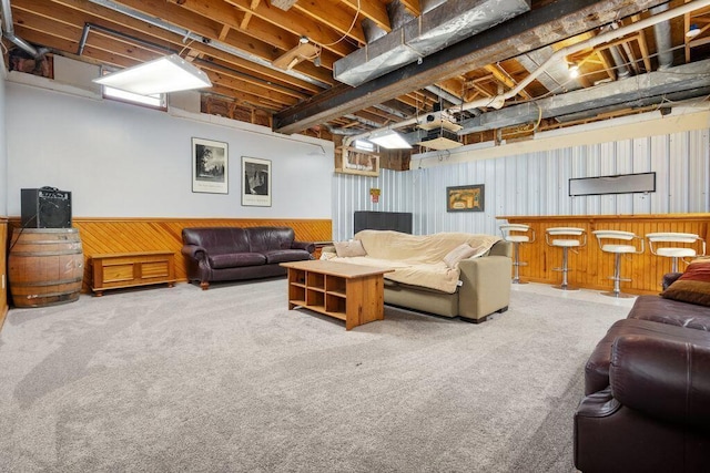 living area with a bar, a wainscoted wall, and carpet flooring