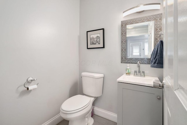 bathroom with toilet, baseboards, and vanity