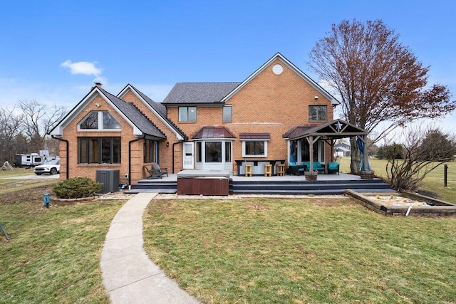 rear view of house with a gazebo, a yard, a wooden deck, and a hot tub