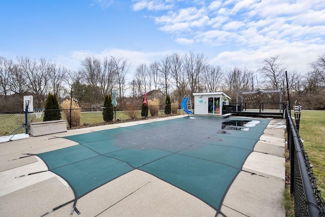 view of swimming pool with fence, an outdoor structure, a fenced in pool, and a water slide