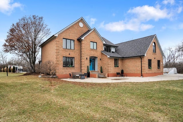 view of front of house with brick siding, a patio, and a front lawn