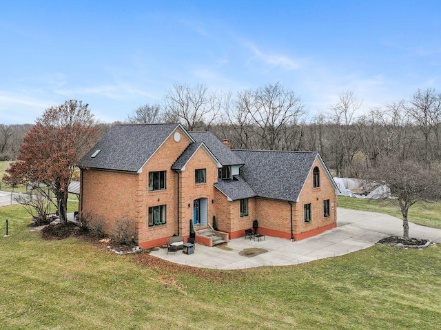 traditional-style home featuring a patio area, a front yard, a chimney, and brick siding