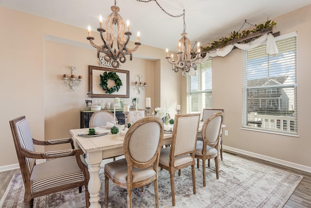 dining room featuring a chandelier, baseboards, and wood finished floors