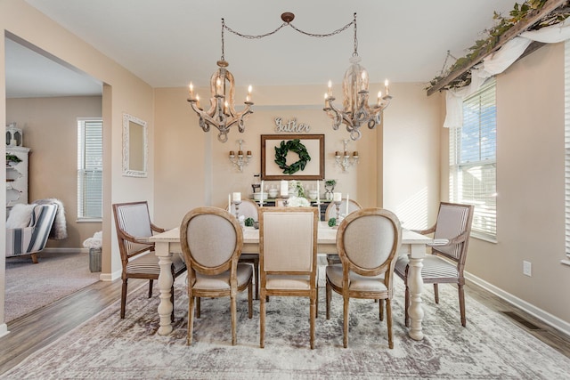 dining space with visible vents, baseboards, a notable chandelier, and wood finished floors