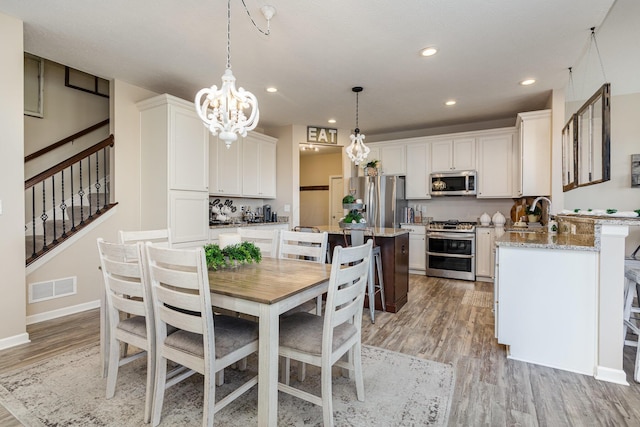 dining area with a chandelier, recessed lighting, visible vents, stairs, and light wood-type flooring