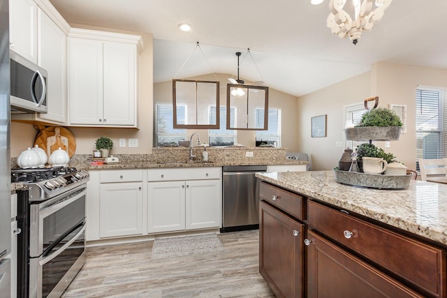 kitchen with pendant lighting, appliances with stainless steel finishes, white cabinetry, a sink, and light wood-type flooring