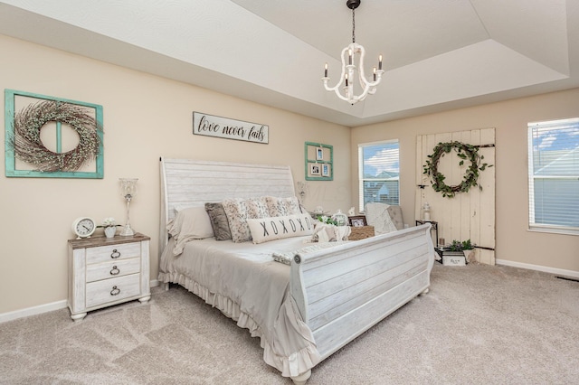 carpeted bedroom with a chandelier, a tray ceiling, and baseboards