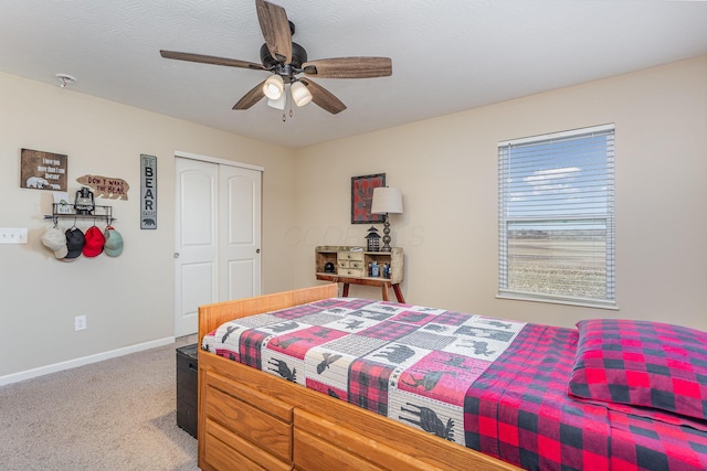 bedroom featuring a closet, light carpet, ceiling fan, a textured ceiling, and baseboards