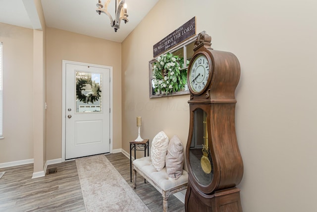 entrance foyer featuring a notable chandelier, visible vents, baseboards, and wood finished floors