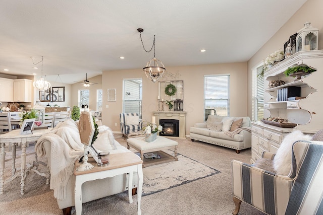 living room with ceiling fan with notable chandelier, carpet floors, a glass covered fireplace, and recessed lighting