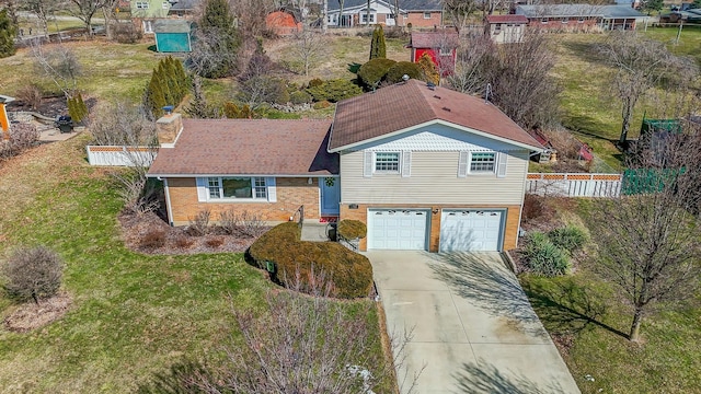 view of front of home with concrete driveway, brick siding, an attached garage, and fence