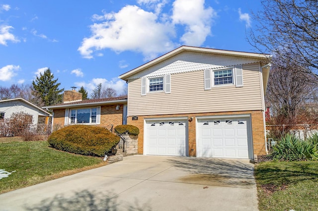 split level home featuring brick siding, a chimney, concrete driveway, an attached garage, and a front yard