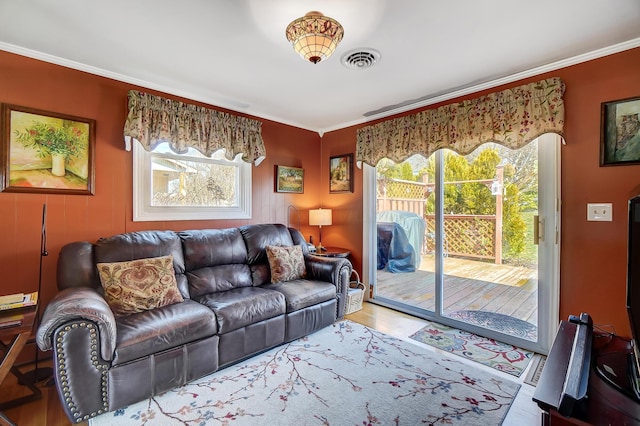 living room with plenty of natural light, wood finished floors, visible vents, and crown molding