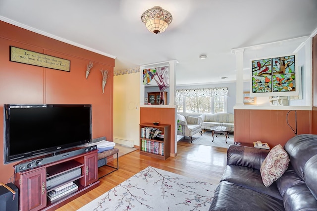 living room with baseboard heating, light wood-style flooring, and crown molding