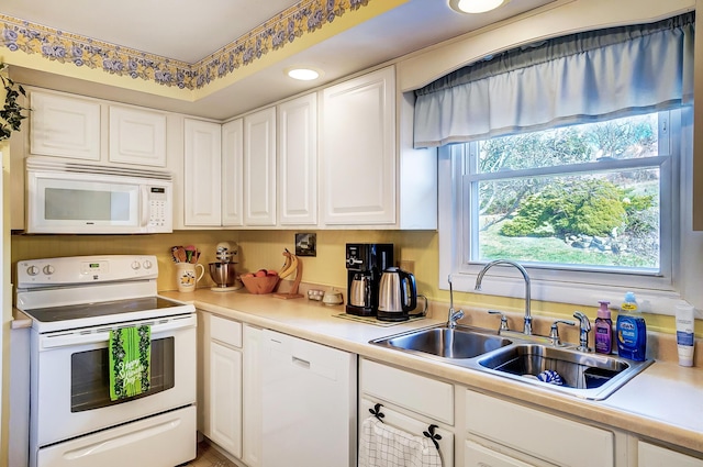 kitchen featuring white cabinets, white appliances, light countertops, and a sink