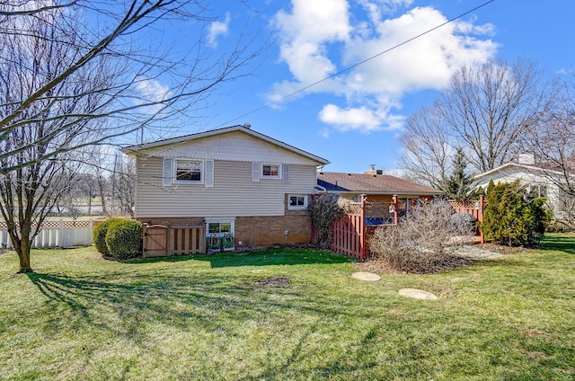 back of property with a yard, brick siding, and fence