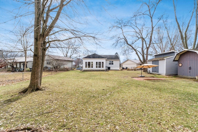 rear view of property featuring a yard, fence, and an outbuilding