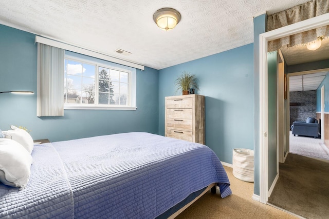 bedroom with visible vents, a textured ceiling, baseboards, and carpet flooring