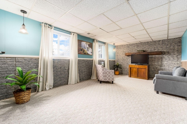 living area featuring a wainscoted wall, carpet, and a drop ceiling